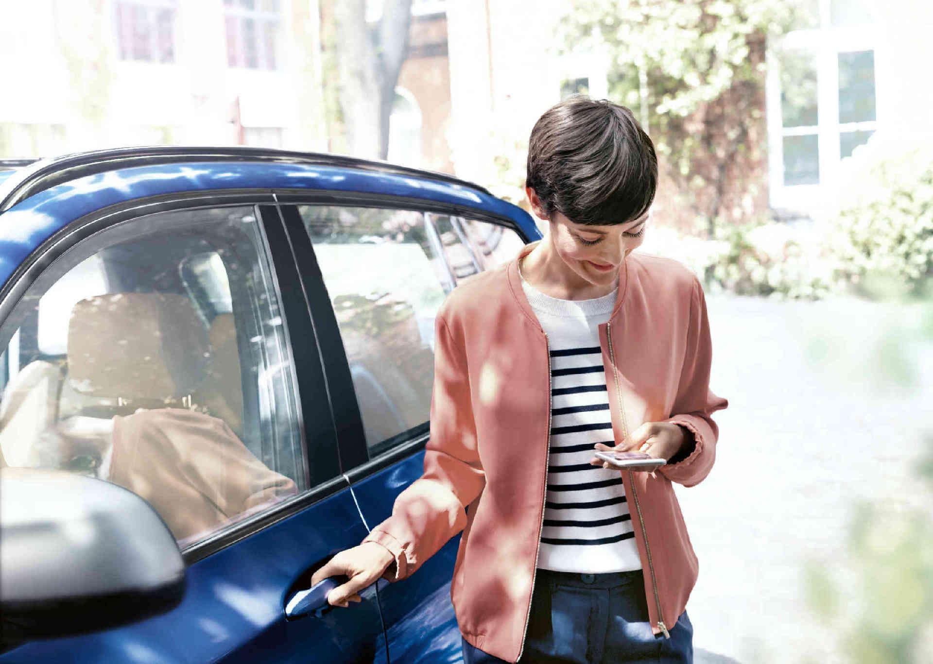 Woman with smartphone next to her car
