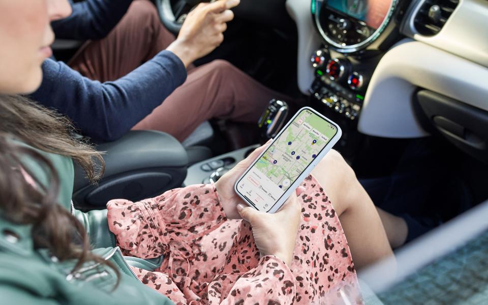Frau auf Beifahrersitz navigiert via Handy