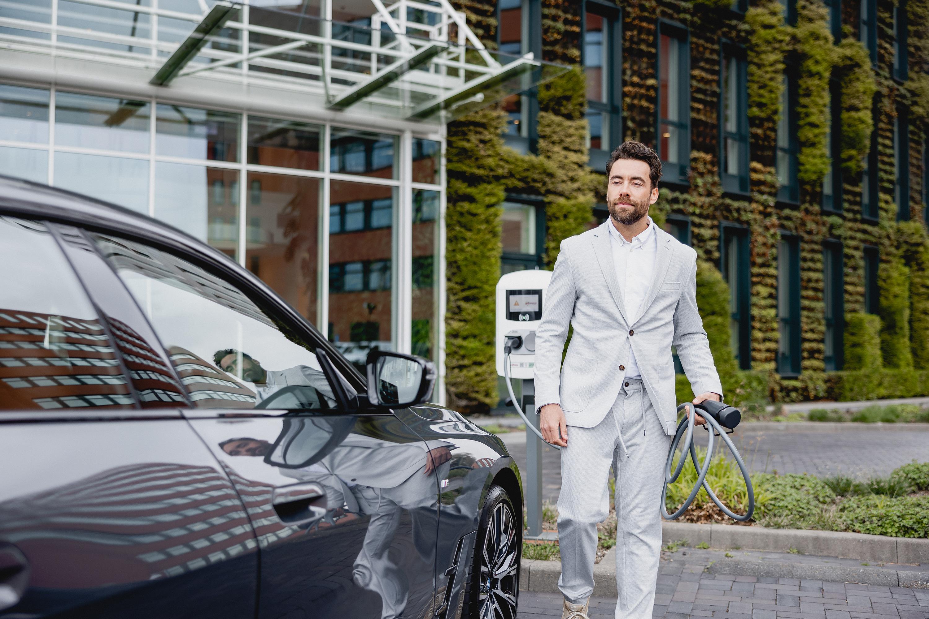 Man in white suit in front of car