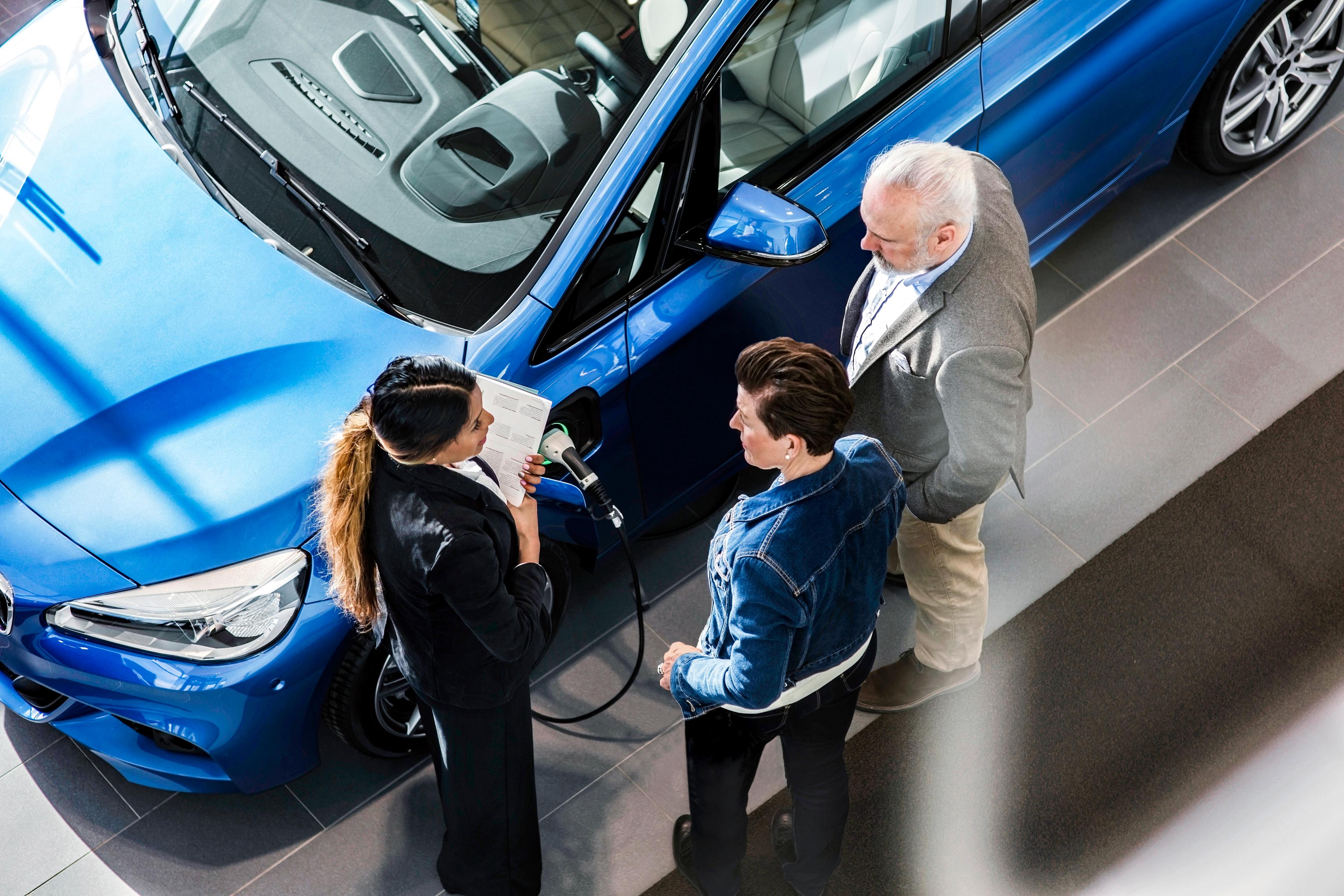 Image of a couple being shown an electric vehicle but a salesperson