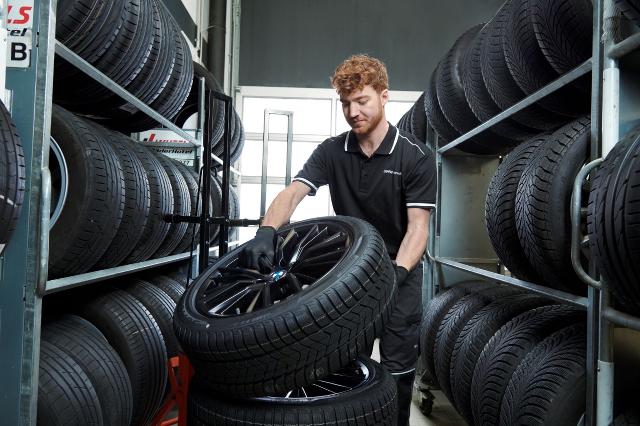Mann befindet sich in einem Reifenlager und stapelt Reifen aufeinander 