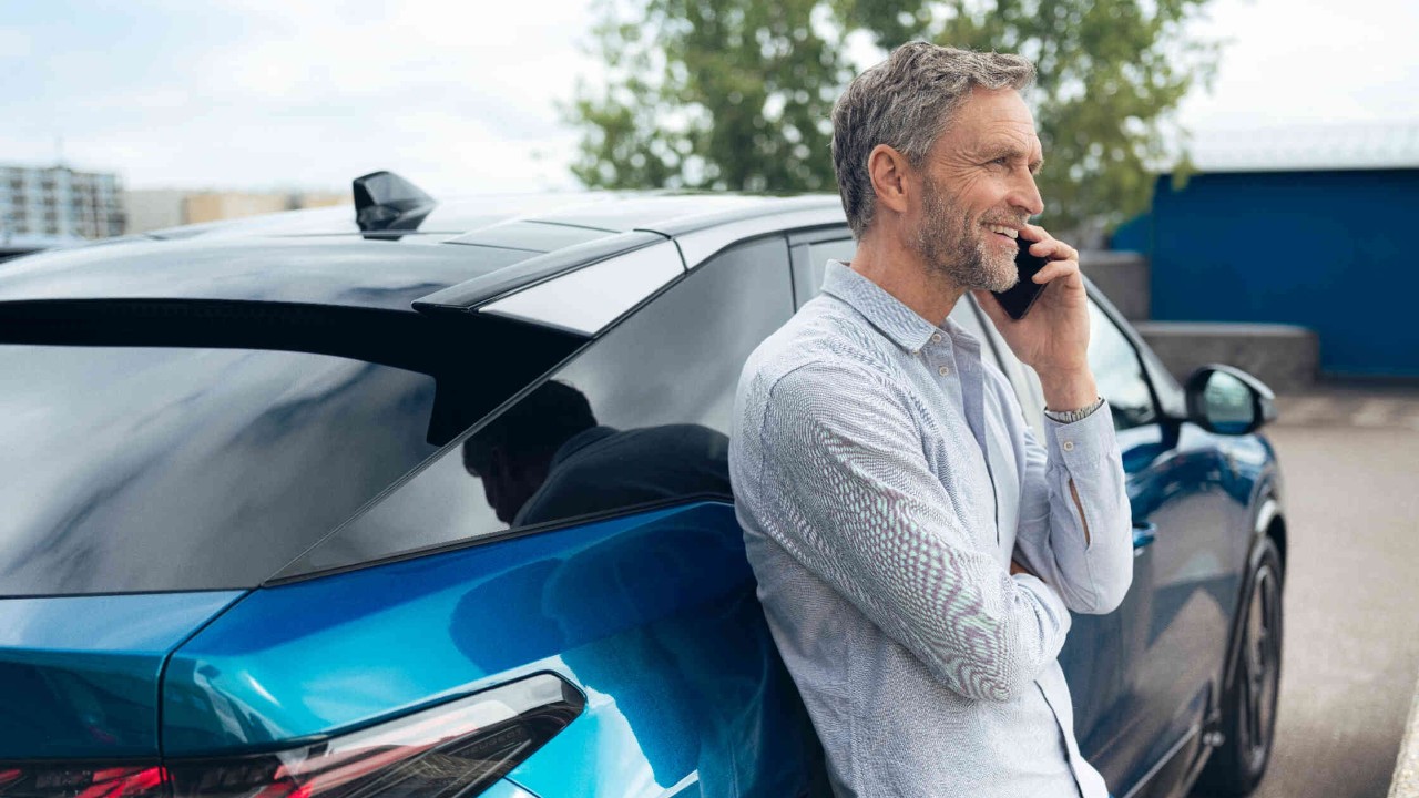 Mann lehnt an modernem Auto.