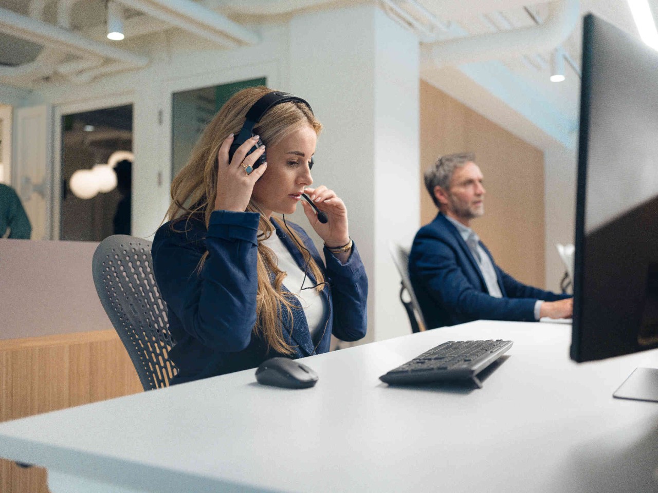 Frau mit Headset am Monitor.