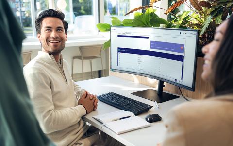 Ein Mann sitzt an einem Schreibtisch. Auf dem PC-Bildschirm ist der Alphabet AI Assistant zu sehen.