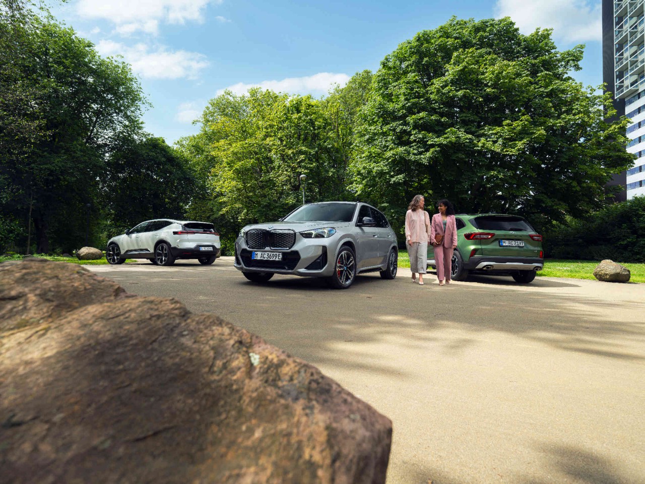 Zwei Frauen gehen zwischen 2 geparkten Autos auf Weg im Park.
