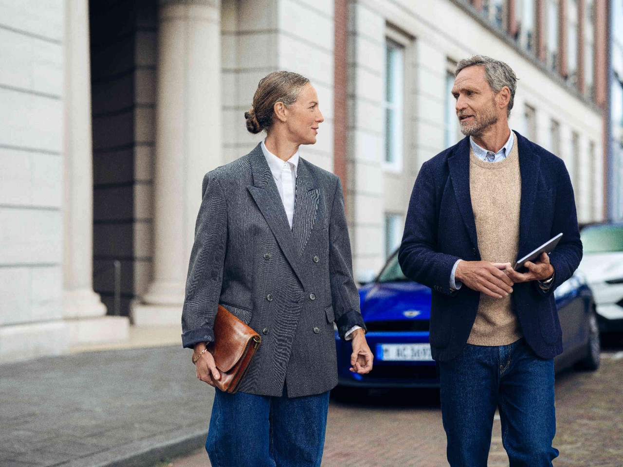 Zwei Personen gehen vor einem Gebaeude mit Saeulen.