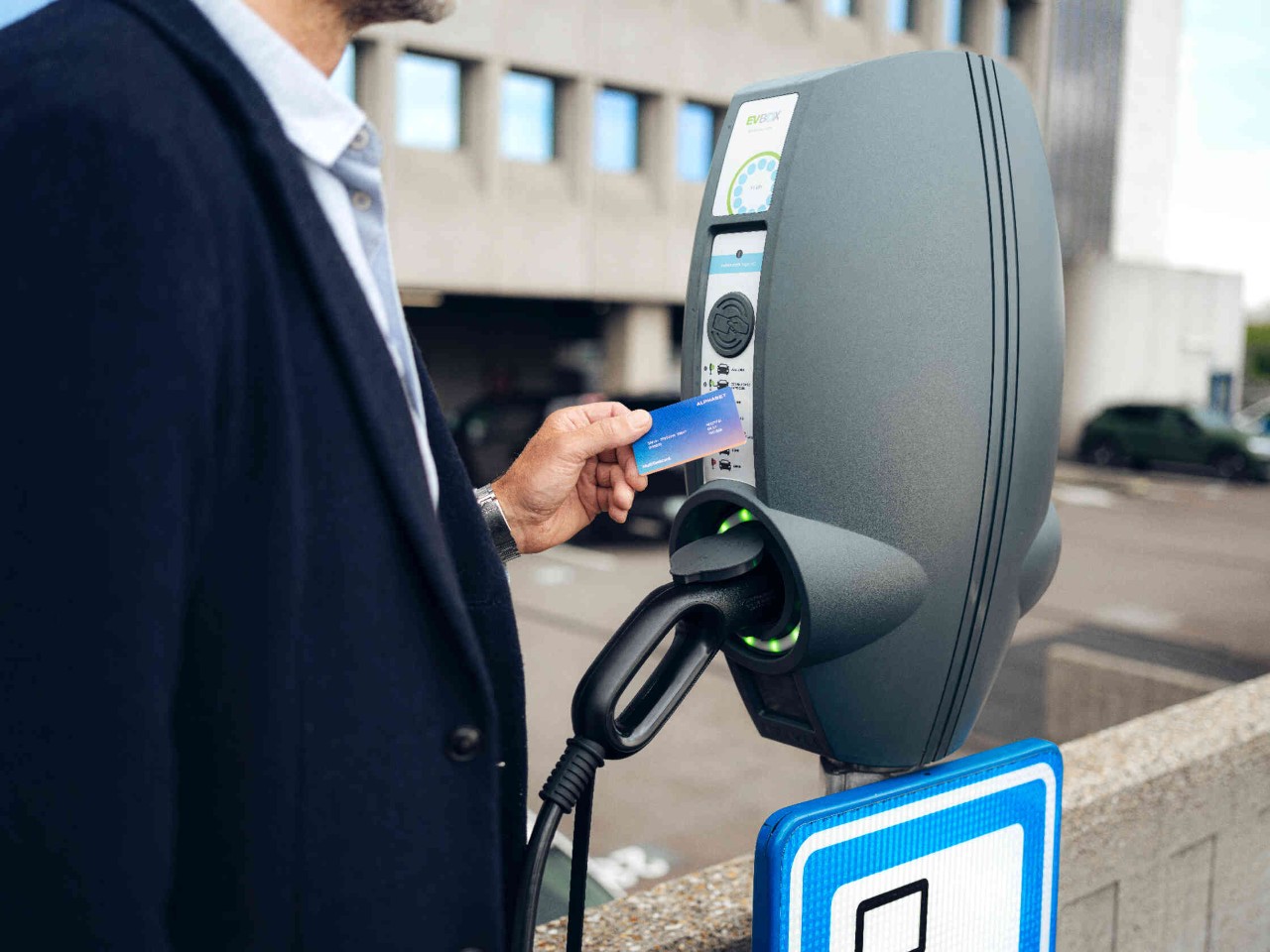 Mann bedient eine Ladestation fuer Elektrofahrzeuge.