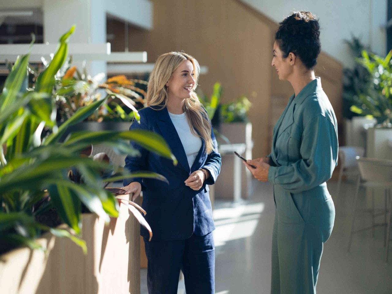 Zwei Frauen interagieren in einem modernen Innenraum mit Pflanzen.