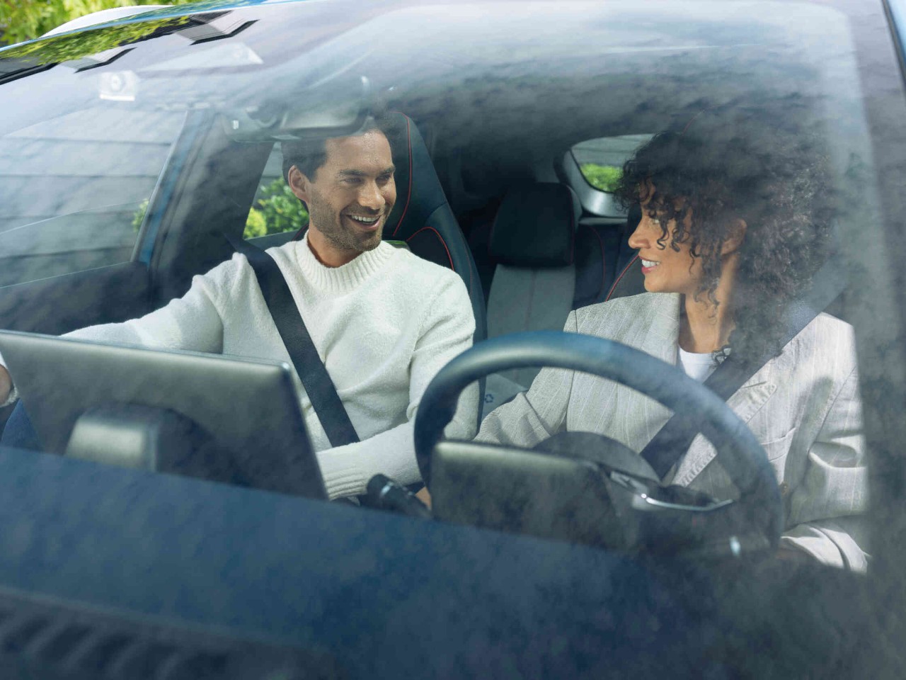 Zwei Personen im Auto mit Sicherheitsgurten Blick durch die Windschutzscheibe.