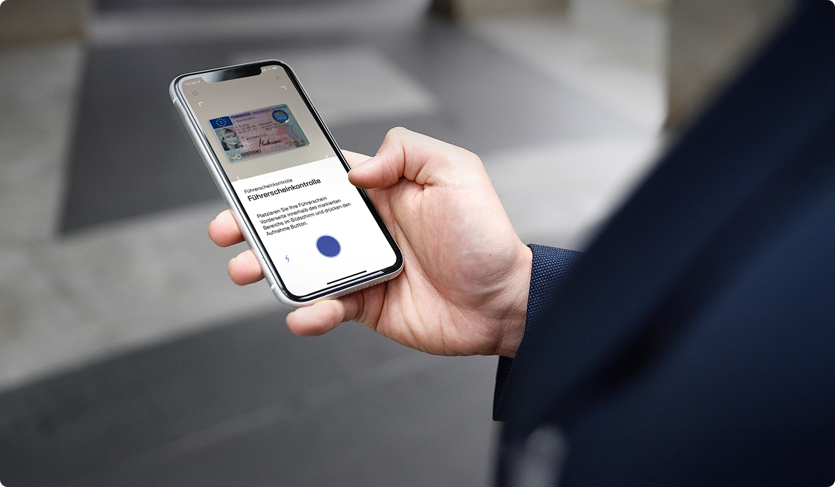 Mann hat Handy in der Hand. Bildschirm zeigt die Führerscheinkontrolle.