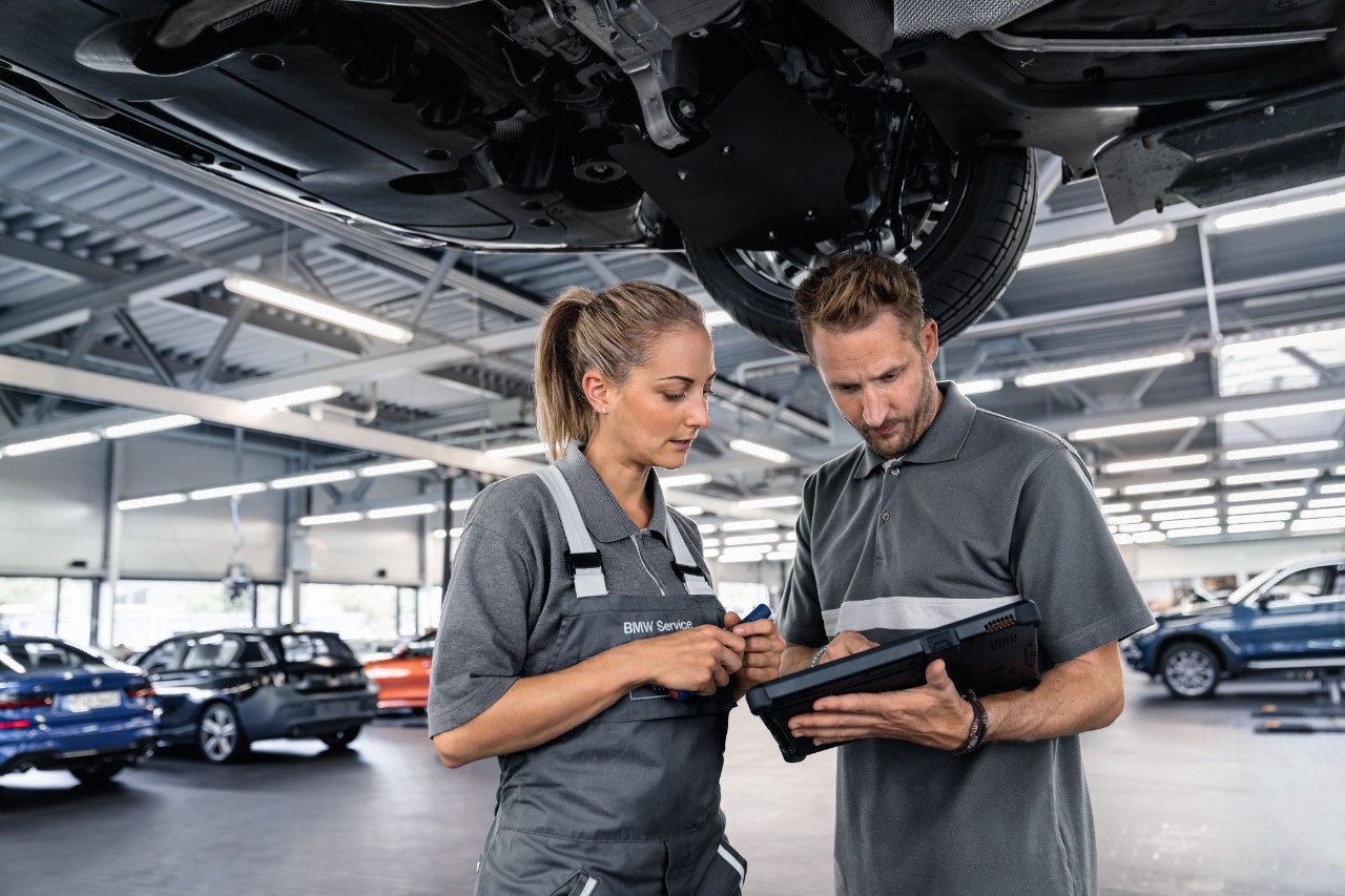 Frau und Mann stehen in einer Werkstatt und schauen auf ein Geraet