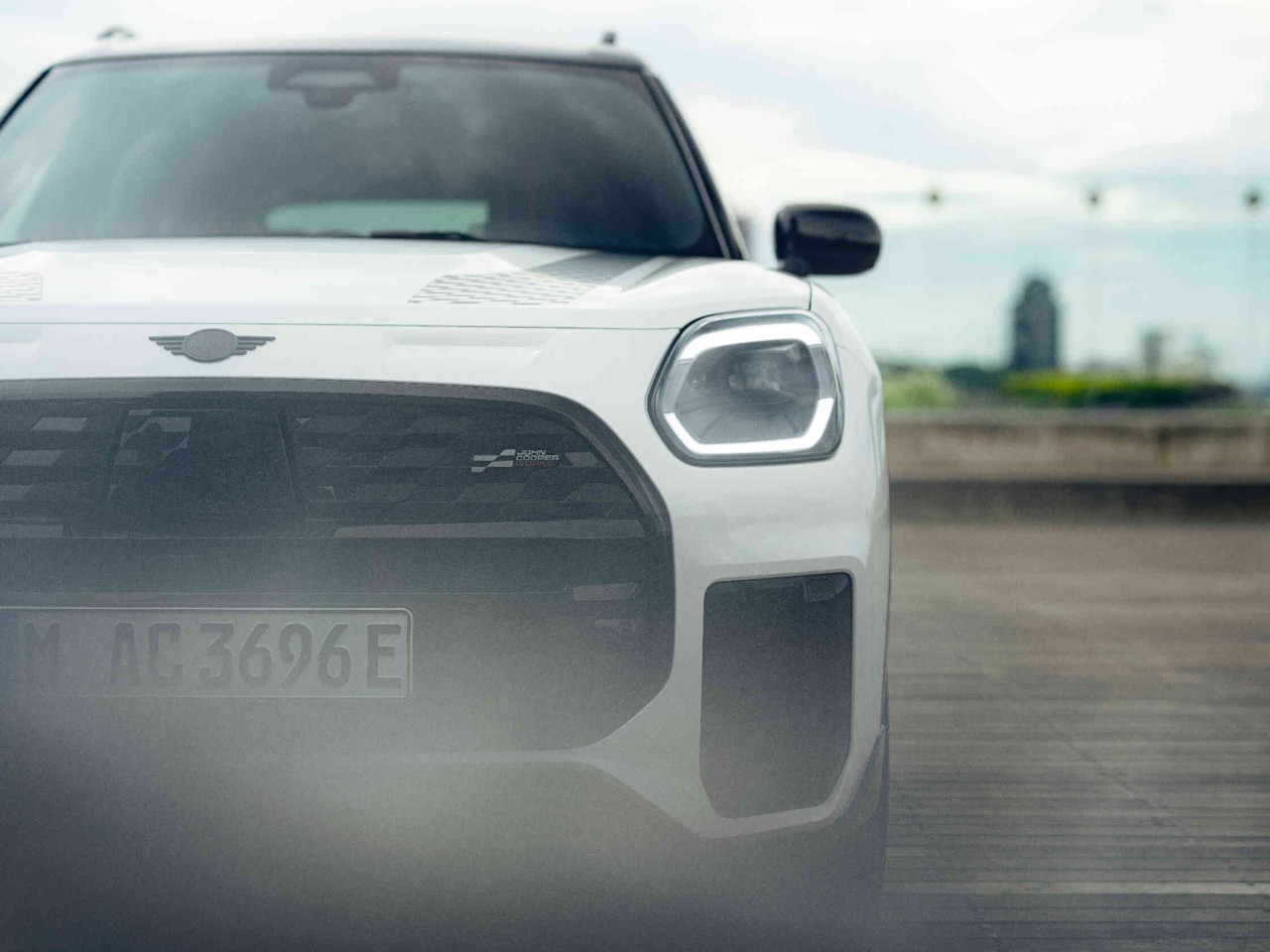 Frontansicht eines weissen Mini auf Holzboden mit verschwommenem Hintergrund.