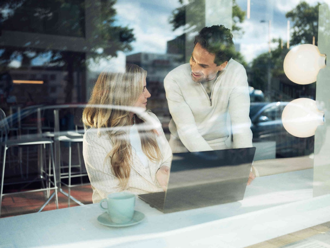 Zwei Personen in einem Caf? arbeiten an einem Laptop.