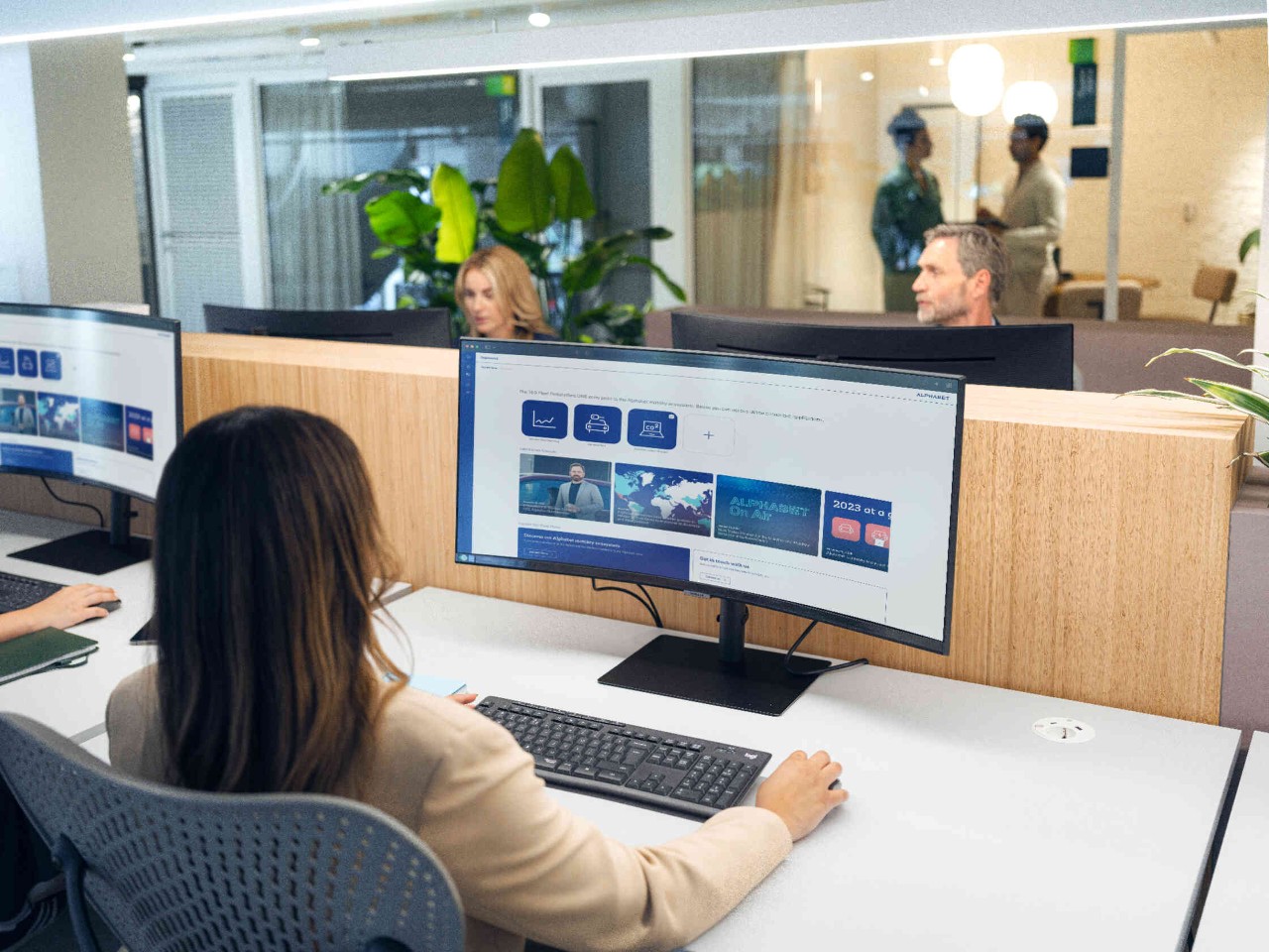 Frau mit dunklen Haaren am gebogenen Bildschirm.