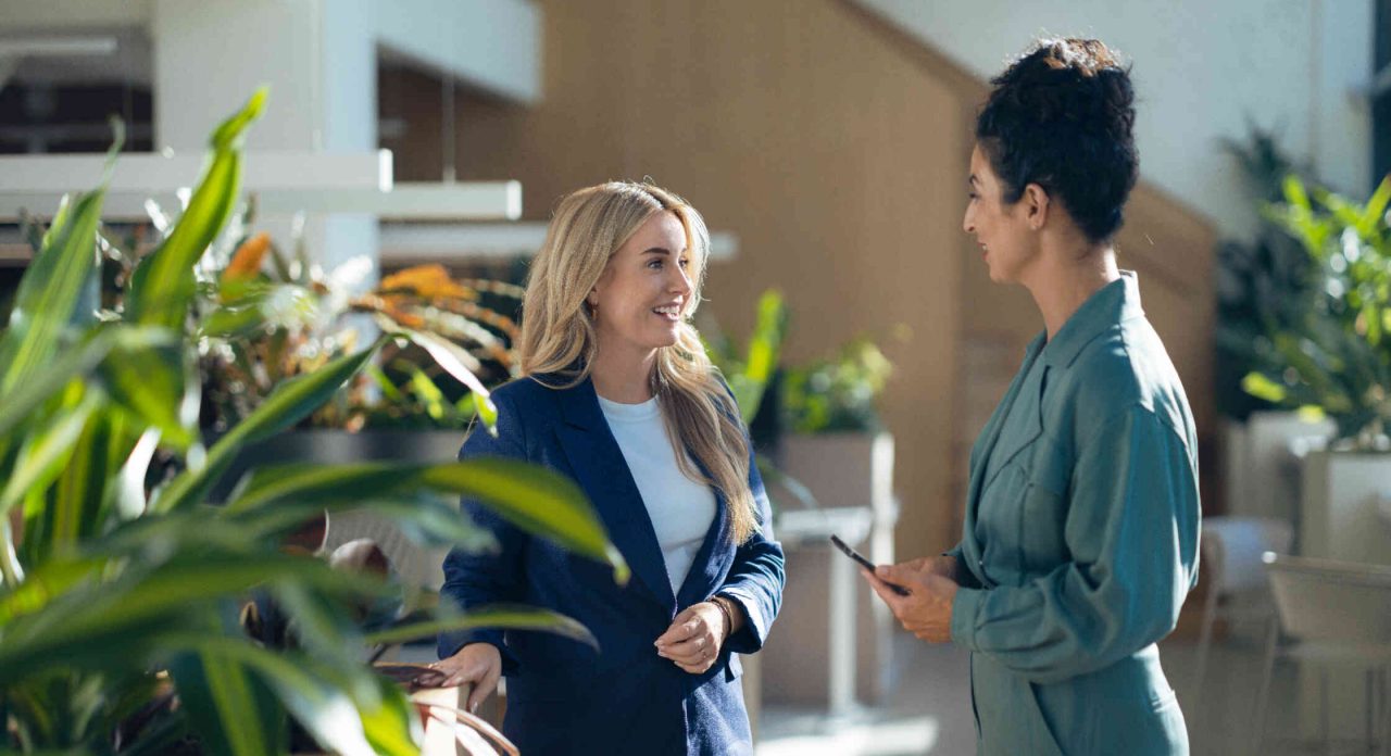 Zwei Frauen interagieren in einem modernen Innenraum mit Pflanzen.