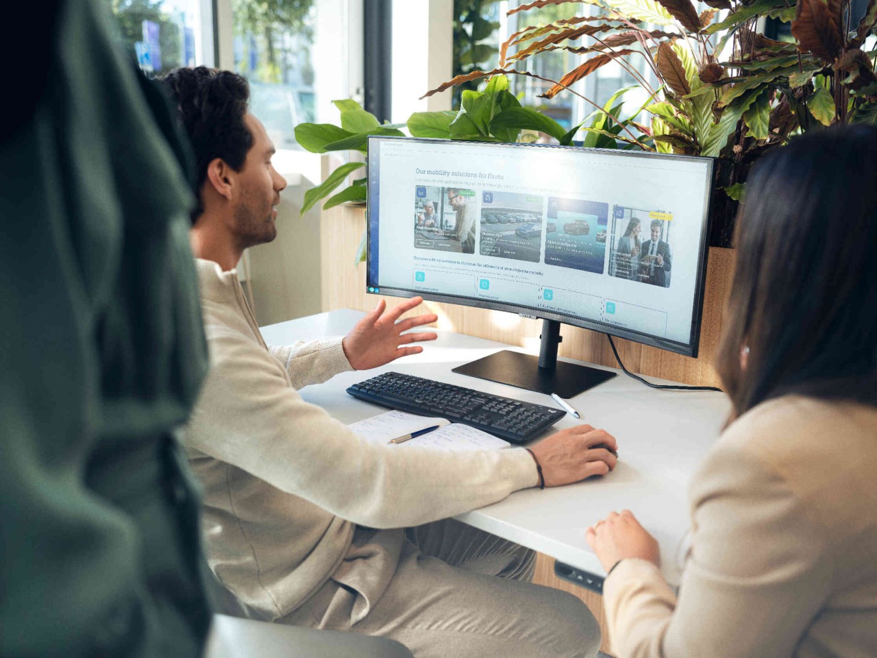 Personen arbeiten vor Bildschirm mit Mobilitaetsloesungen in Buero.
