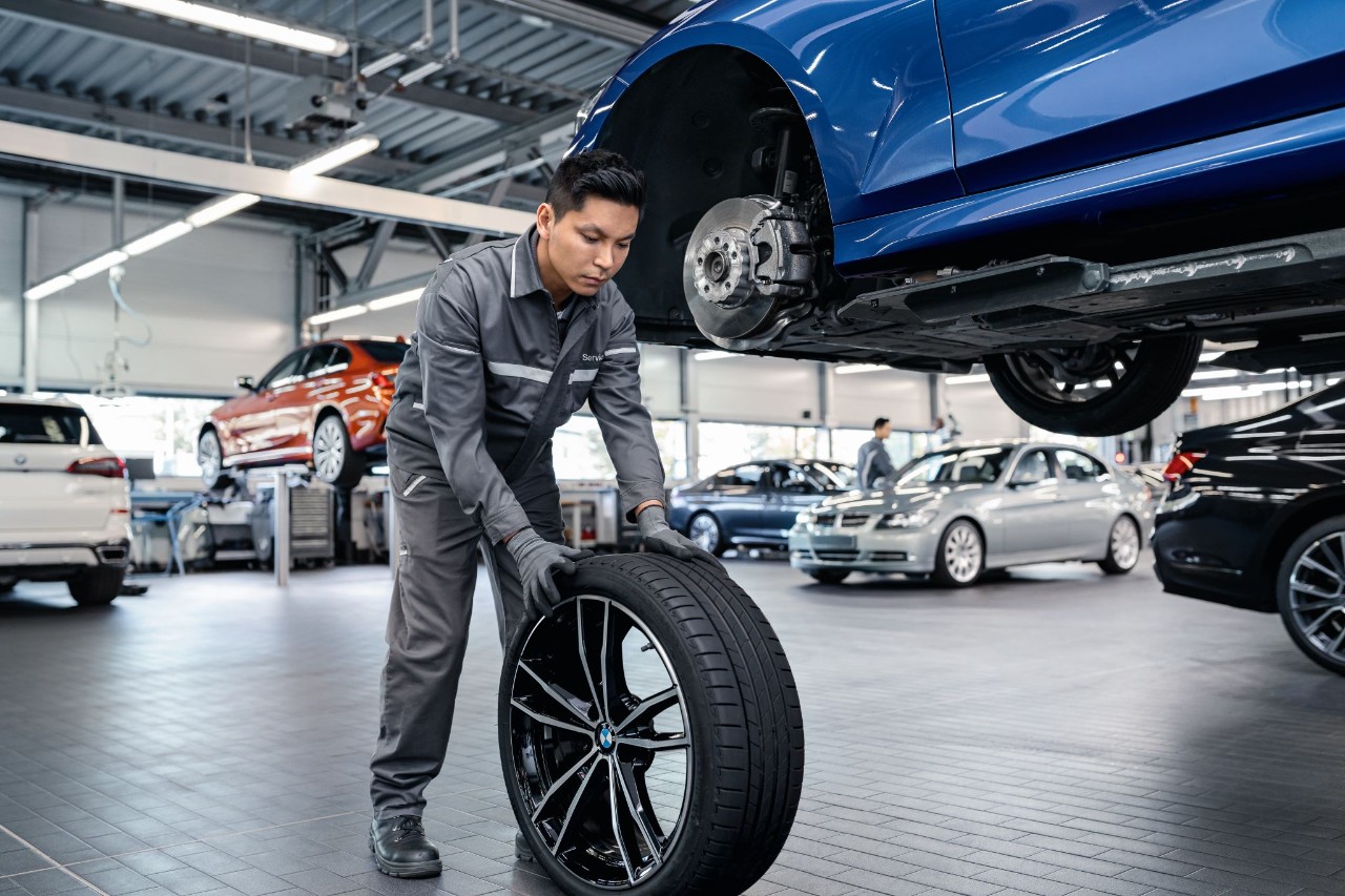 Mann rollt in einer Werkstatt einen Reifen 