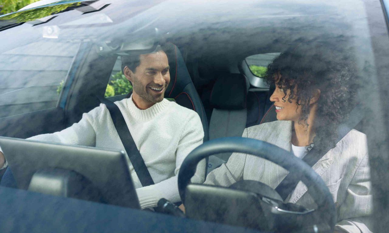 Zwei Personen im Auto mit Sicherheitsgurten Blick durch die Windschutzscheibe.