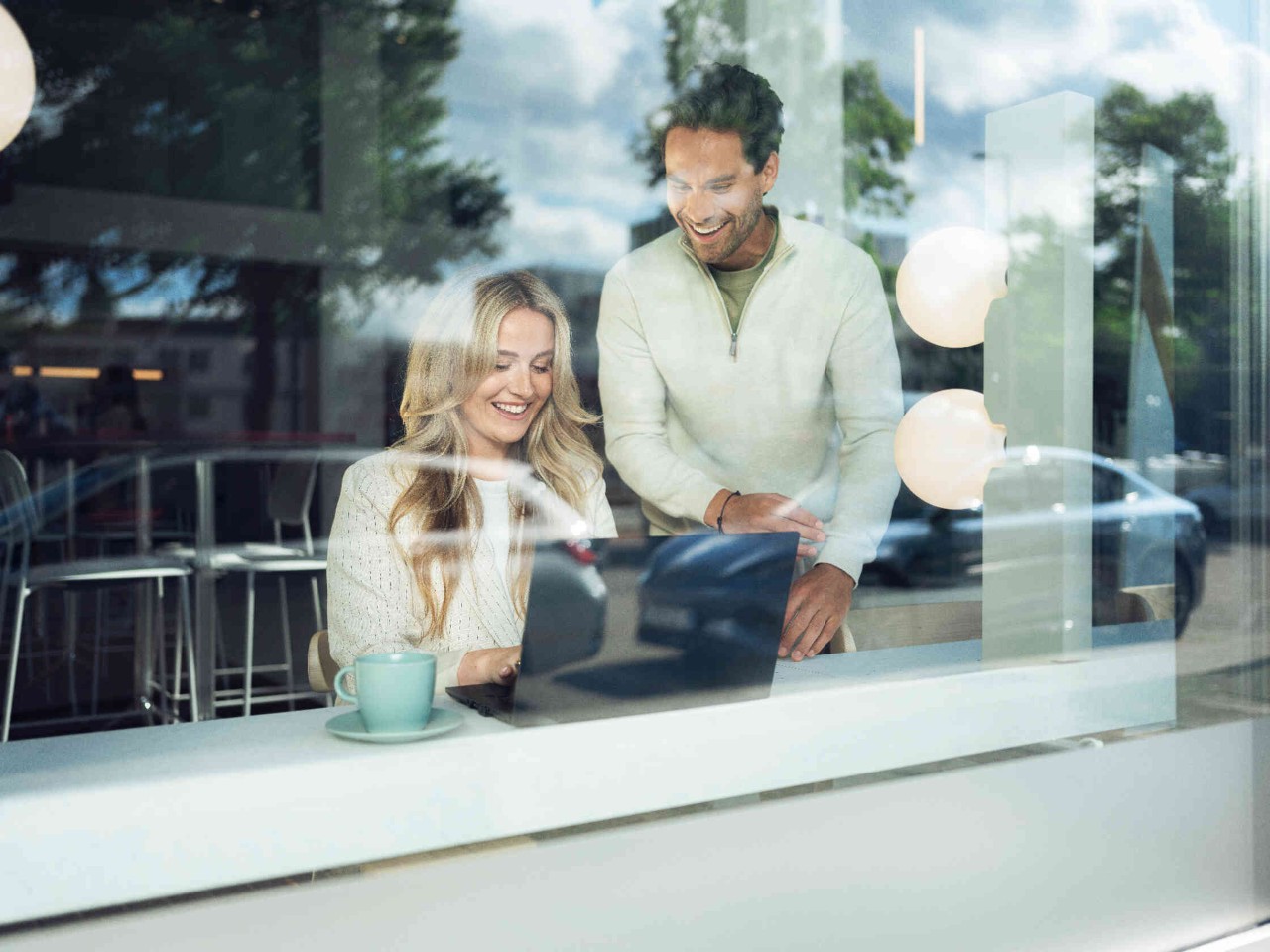 Zwei Personen in einem Caf? arbeiten an einem Laptop.