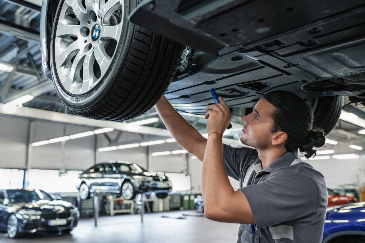 Mann inspiziert den Unterboden eines Fahrzeugs 