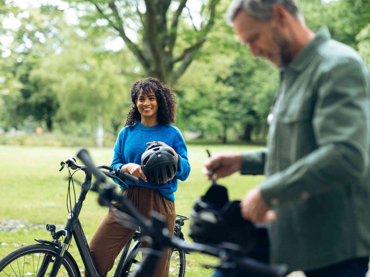 Frau und Mann mit Fahrraedern im Park.