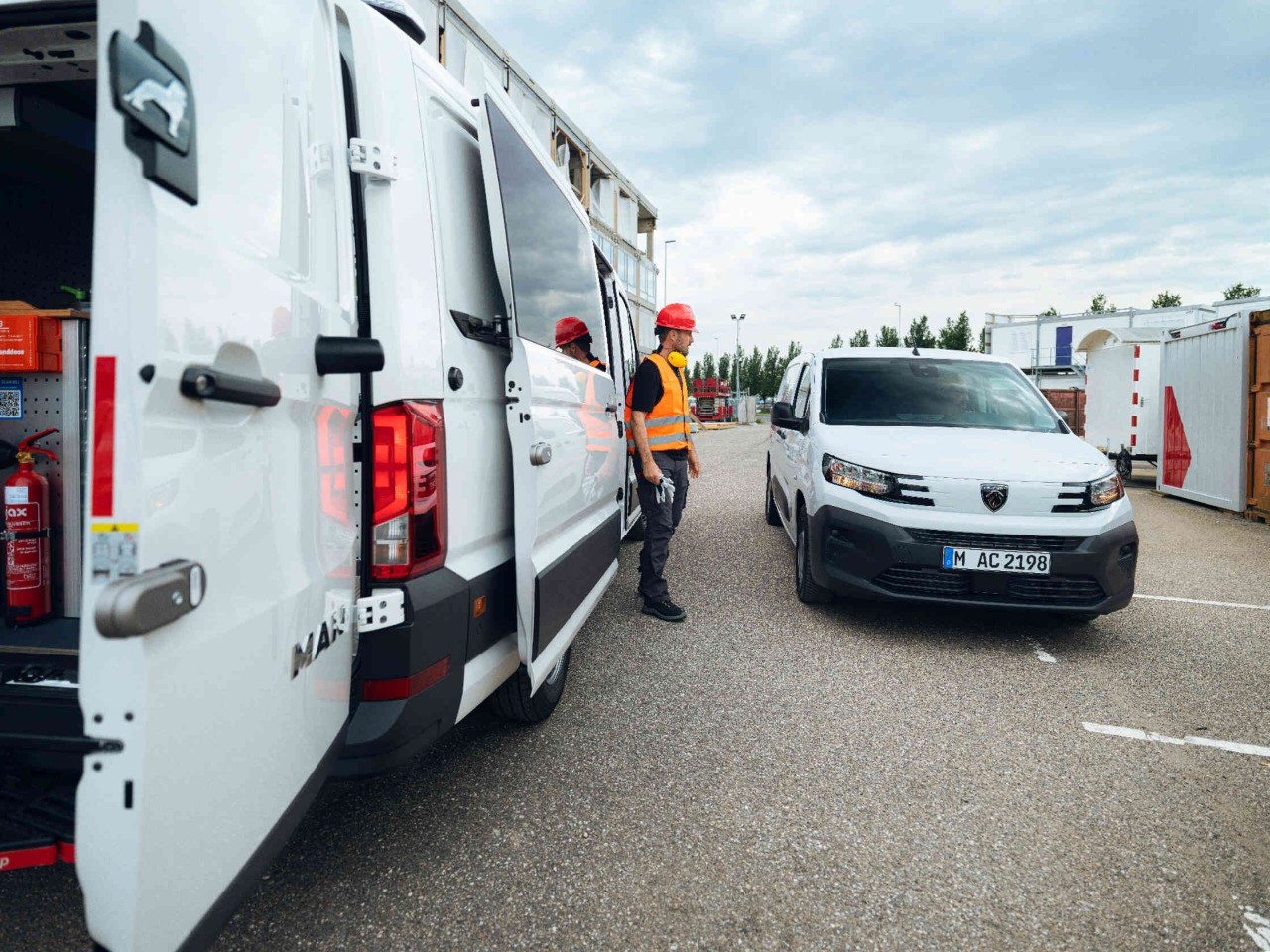 Person mit rotem Helm und Warnweste interagiert mit Auto auf Baustelle.
