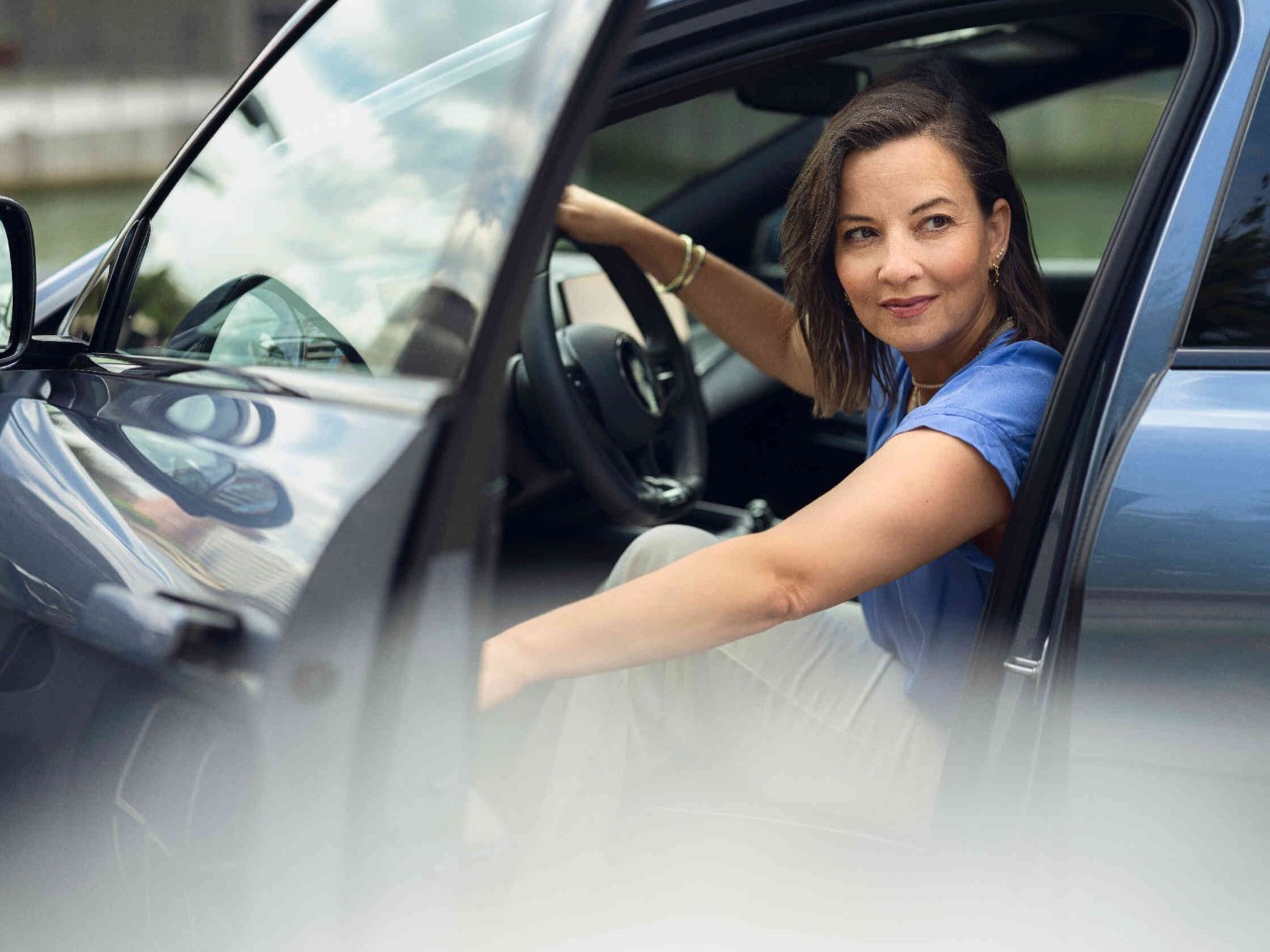 Eine Frau ?ffnet oder schlie?t die Autot?r von innen und blickt dabei nach hinten um den Verkehr zu beobachten.