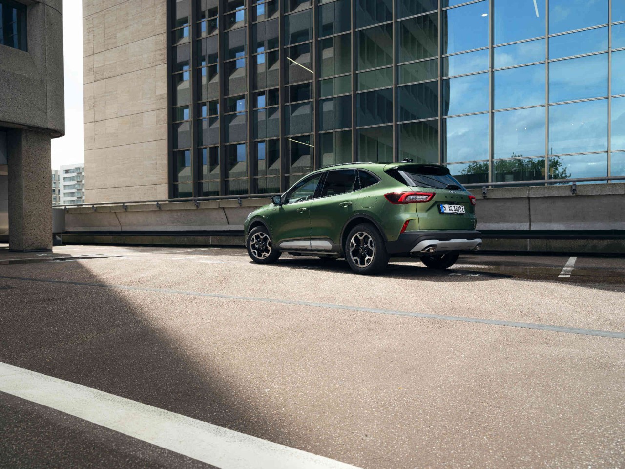 Gruener SUV auf Parkplatz vor Buerogebaeude.