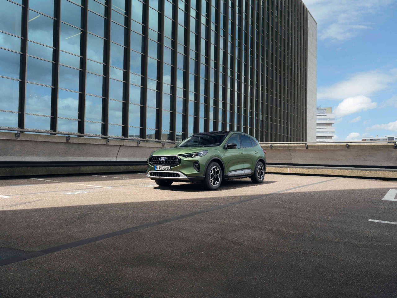 Gruener Ford auf Parkplatz vor Buerogebaeude.