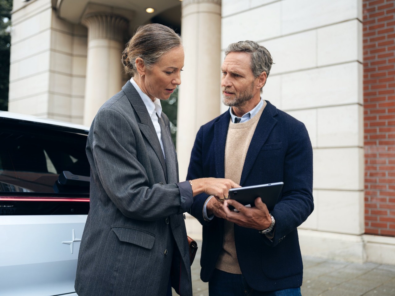 Woman standing next to a man holding an ipad