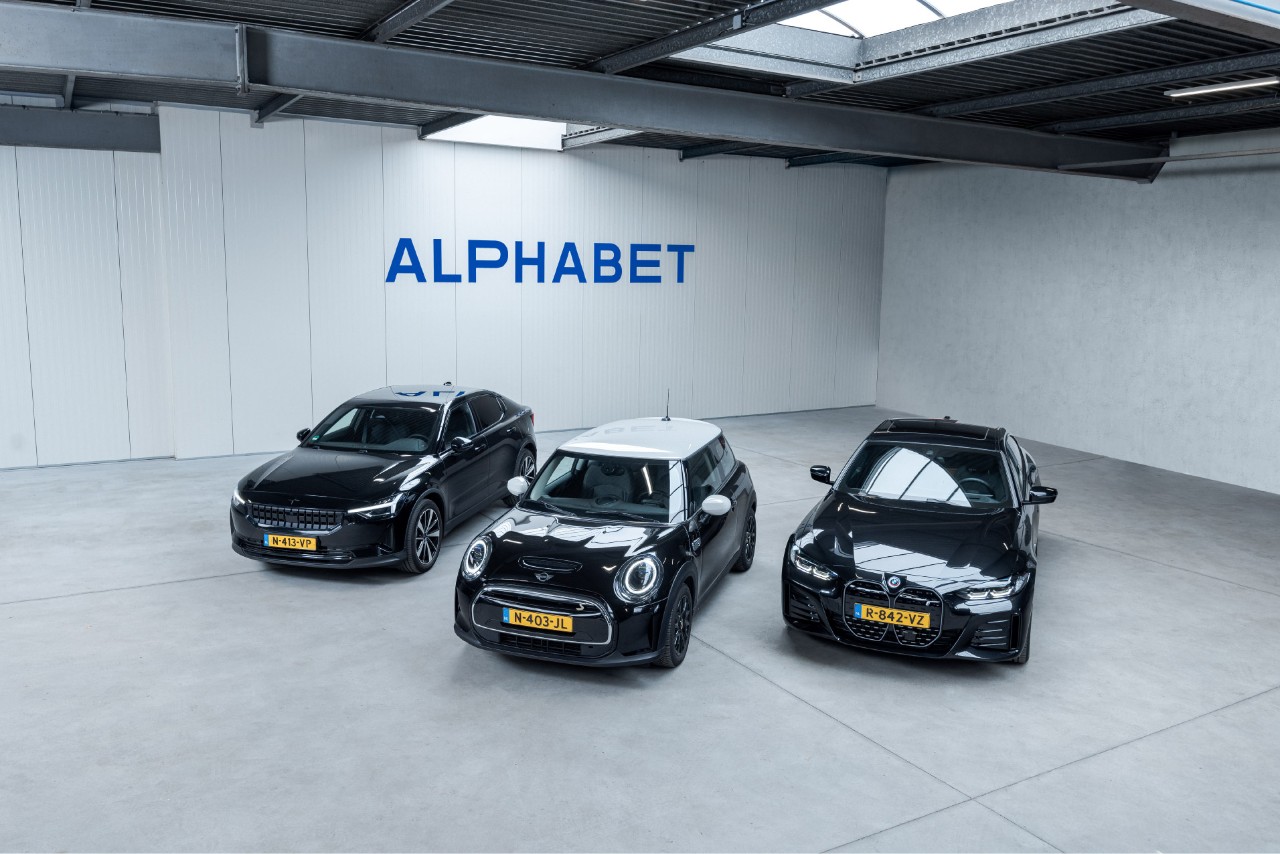 Three cars parked in front of a wall with the Alphabet logo on it. 