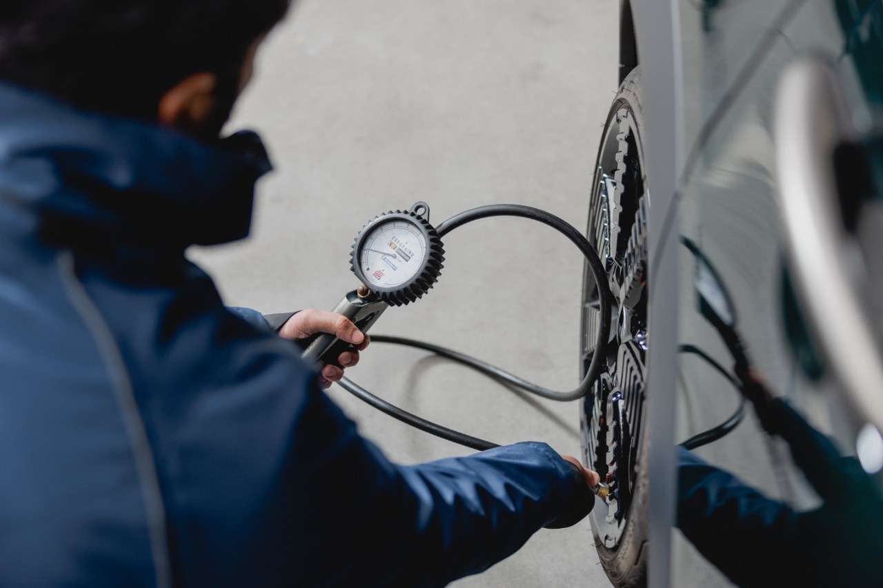 Man using a device to check tire pressure on a vehicle.