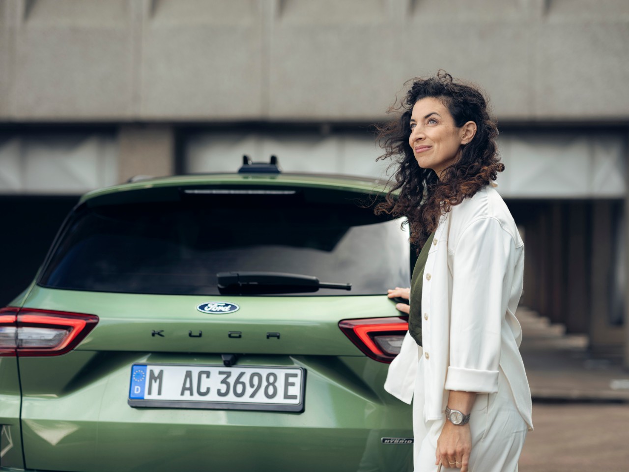 Mann sitzt auf Fahrersitz eines stehendes Autos schaut auf sein Handy Fahrertuer steht offen.