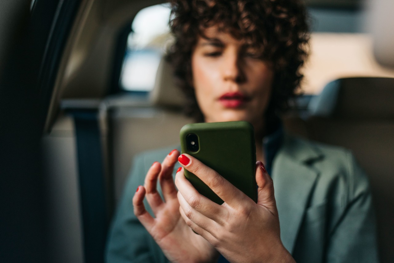 Person sitting in a car, on their smartphone.