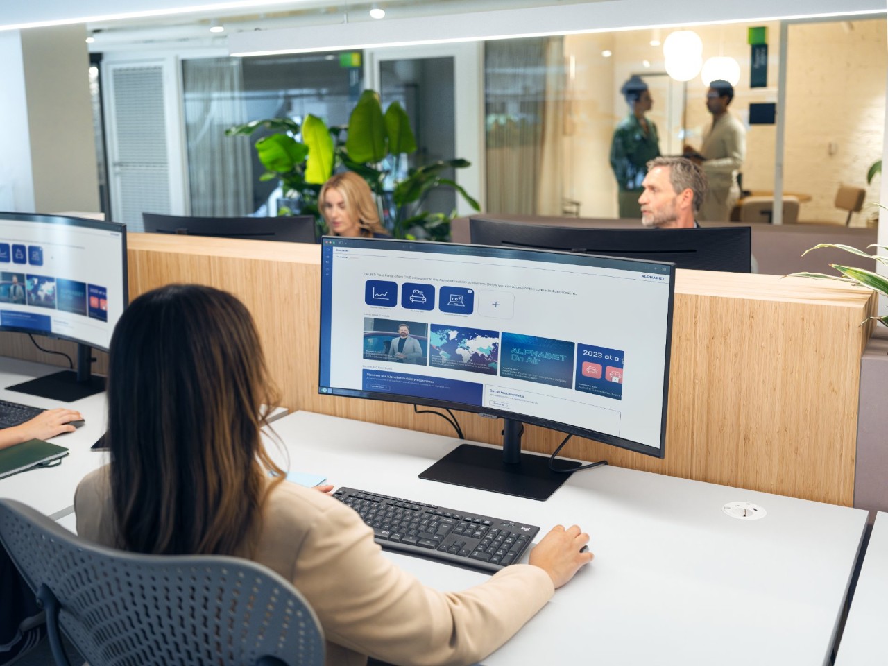 Woman with dark hair at a curved monitor.