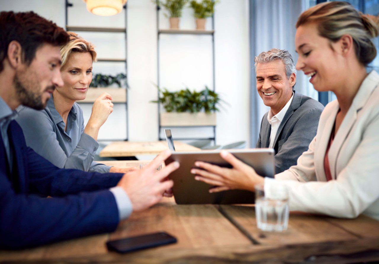 gente en una sala de reuniones mirando una tablet