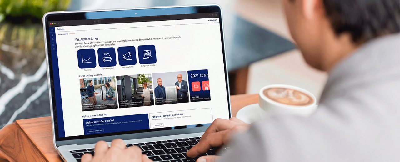 Hombre en cafeteria mirando el 360 Fleet Portal de Alphabet en su ordenador