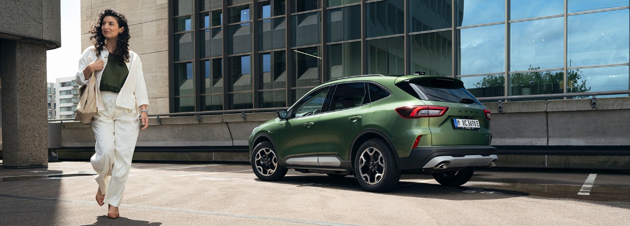 chica vestida de blanco al lado de un coche Kuga verde