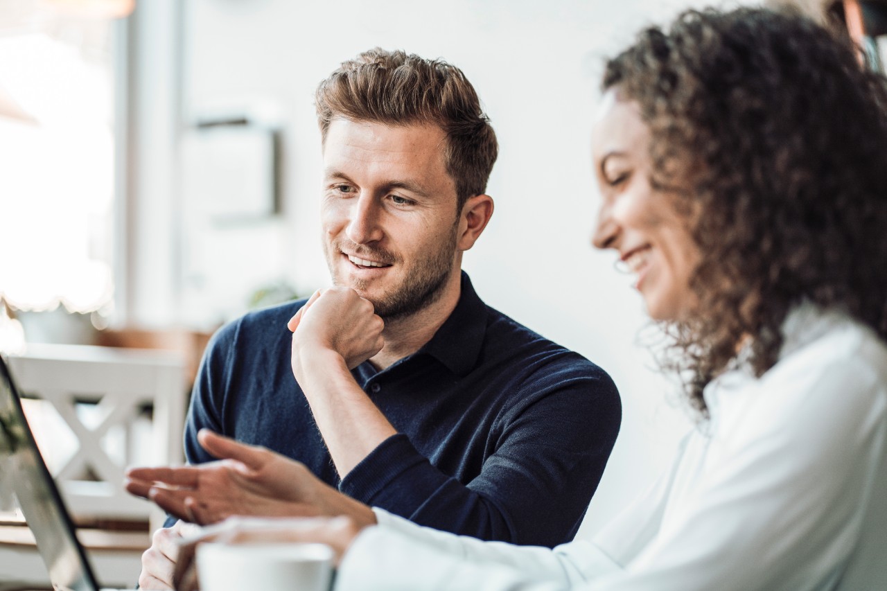 Hombre y mujer en un meeting de trabajo en su oficina moderna. CHico y chica riendose mientras miran la pantalla de un ordenador