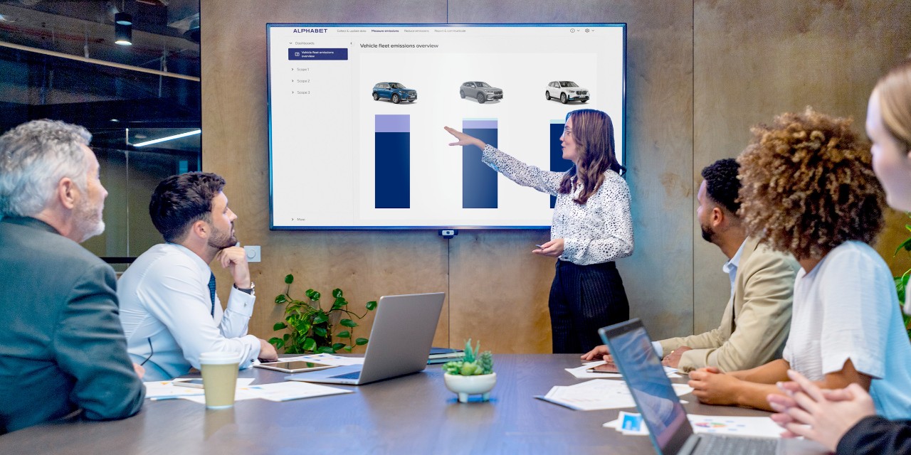 Mujer presentando delante de su equipo mostrando una pantalla con detalles