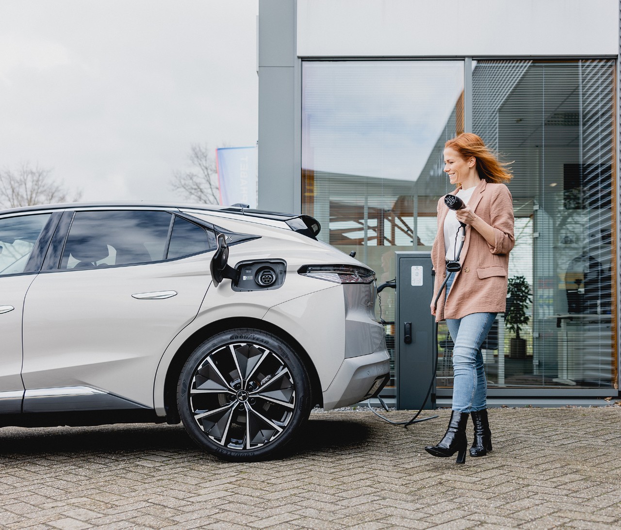 Mujer yendo a cargar su coche gris.