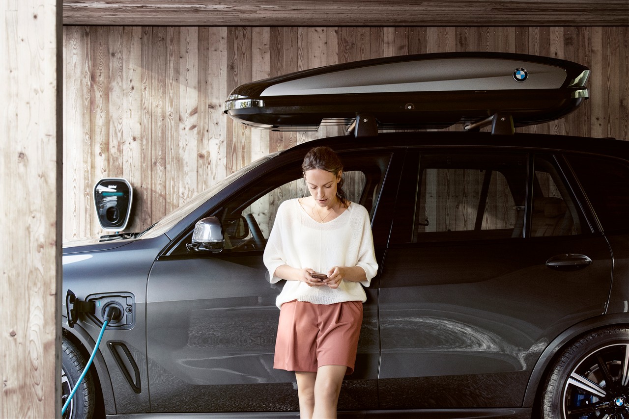 Mujer apoyada a su coche mirando el mobil