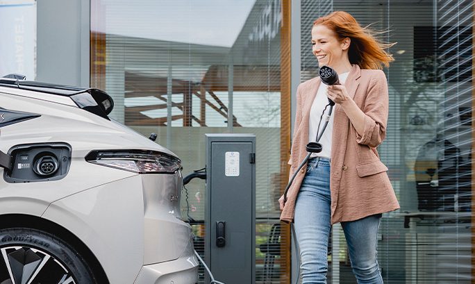 Mujer cargando su coche eléctrico gris.