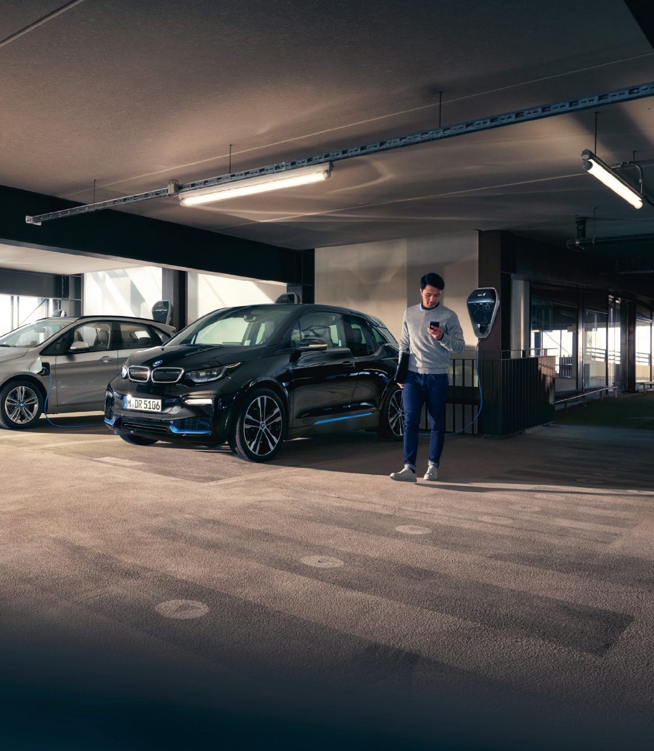 Hombre mirando al telefono mientras se carga su coche electrico. Hombre mirando al telefono mientras se carga su coche electrico.