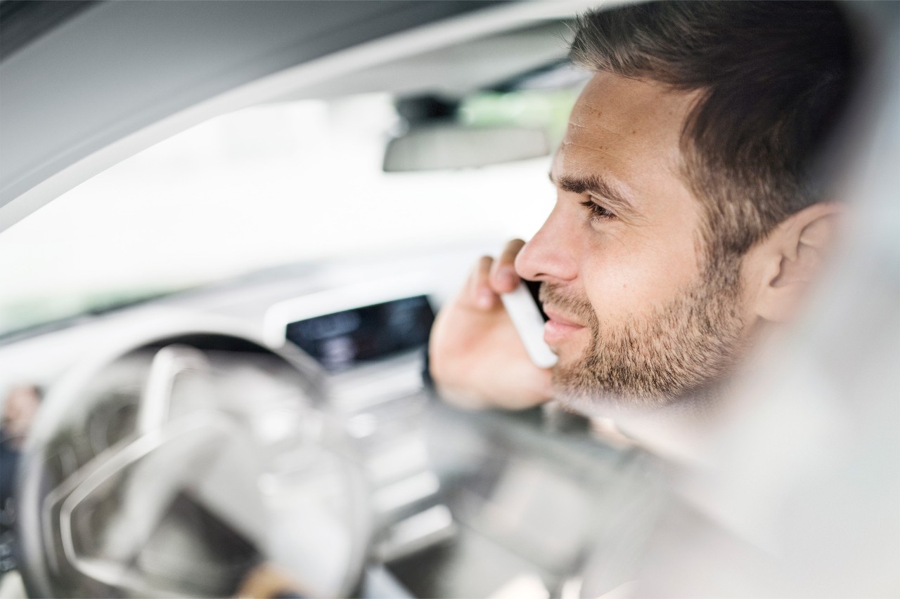 Hombre al telefono dentro de su coche estacionado.