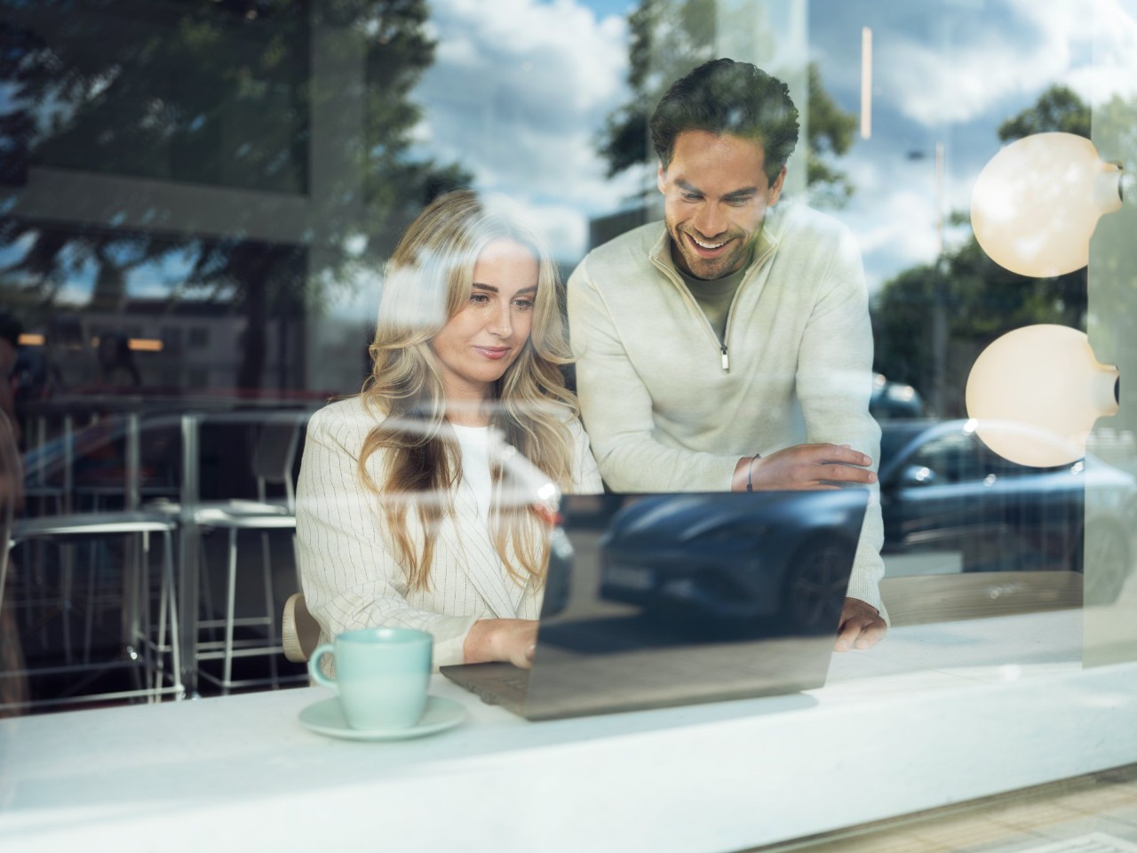 Dos personas en una cafeteria trabajando en un ordenador.