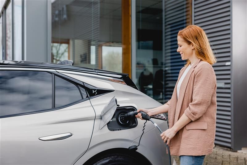 Mujer cargando su vehiculo electrico en casa