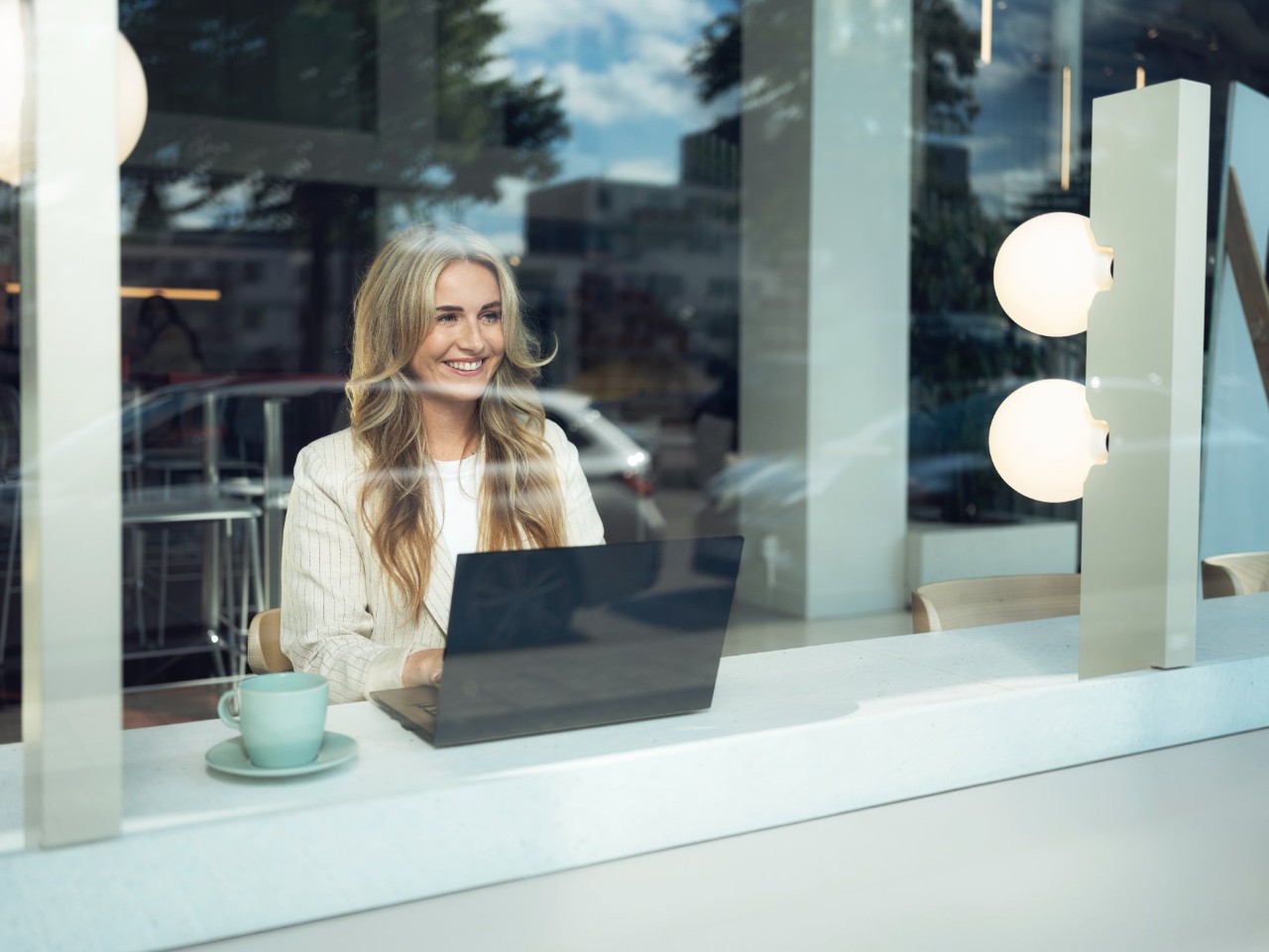 Chica rubia con un ordenador tras un cristal