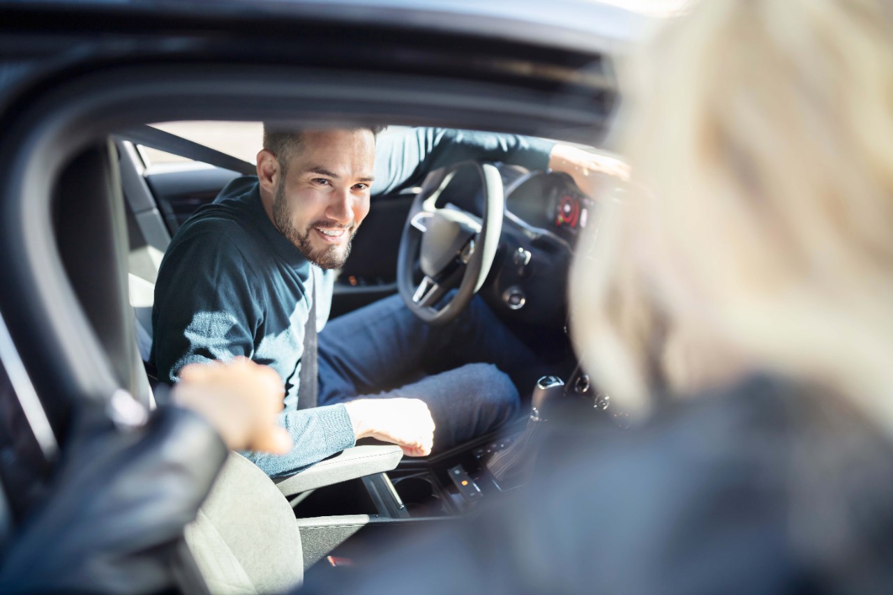 Chico en el coche hablando con chica rubia