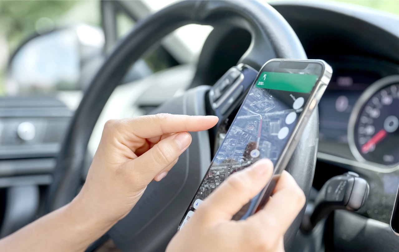 manos sujetando un movil dentro del coche al lado del volante